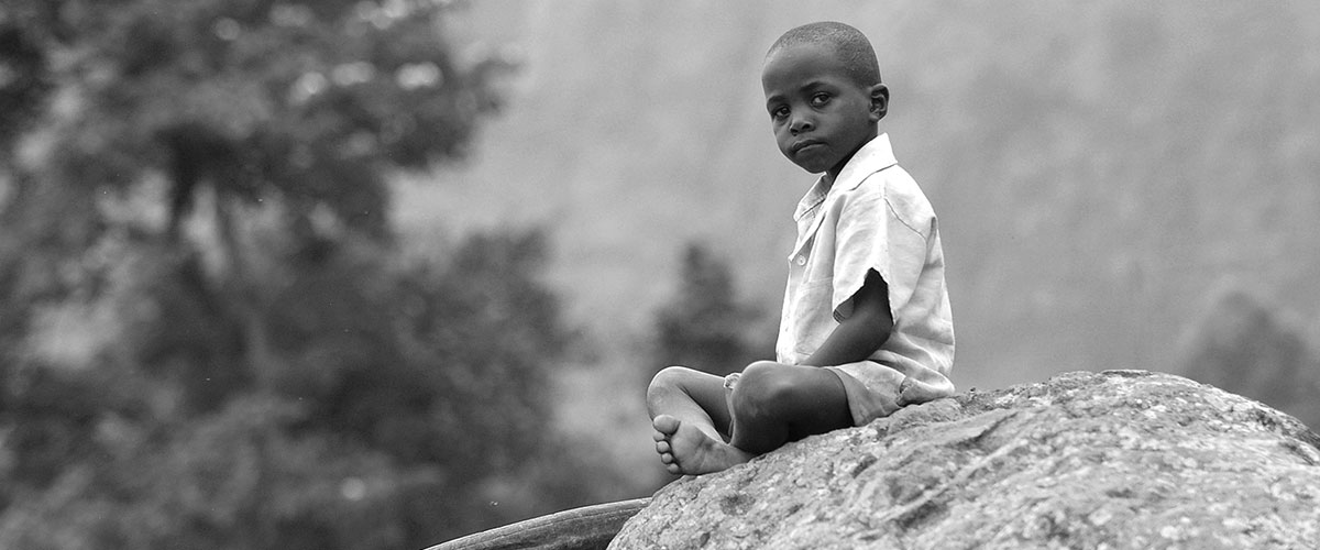 Poor Black Boy sitting on a rock